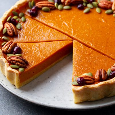 Pumpkin Pie Lined With Pecans And Sliced Sitting On A Plate.