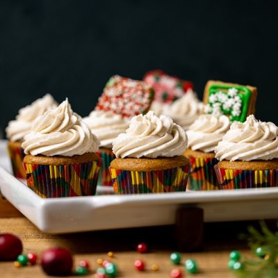 A Platter of Vegan Gingerbread Cupcakes is Surrounded by Christmas Cookies and Christmas Decor.