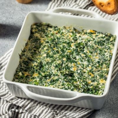 Healthier Spinach & Artichoke Dip in Square Ceramic Baking Dish Set on Tea Towel