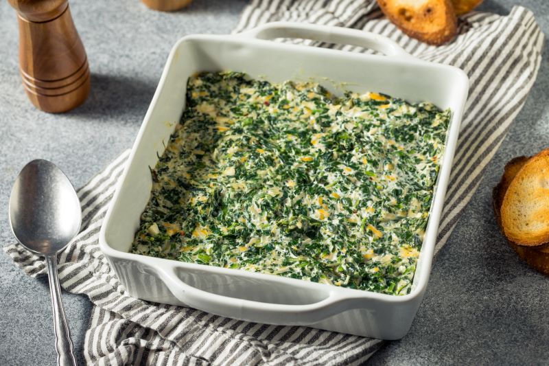 Healthier Spinach & Artichoke Dip in Square Ceramic Baking Dish Set on Tea Towel