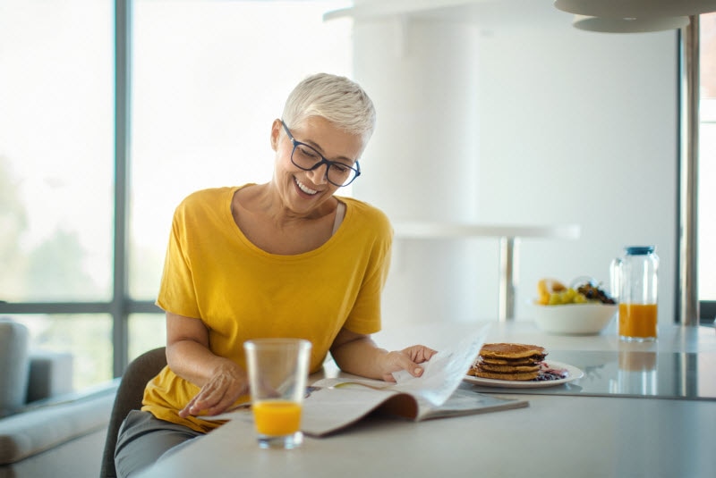 Middle-Aged Women Trying Cognitive Health Solutions Reading While Eating Breakfast at Kitchen Counter Table