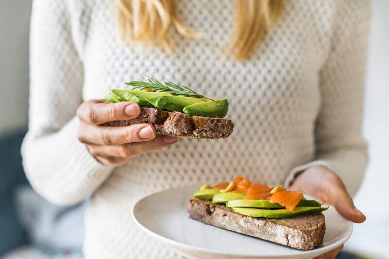 Woman In White Sweater Holding Avocado Toast
