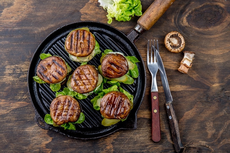 A Grill Pan Holds Six Portobello Mushroom Burgers With Grill Marks.