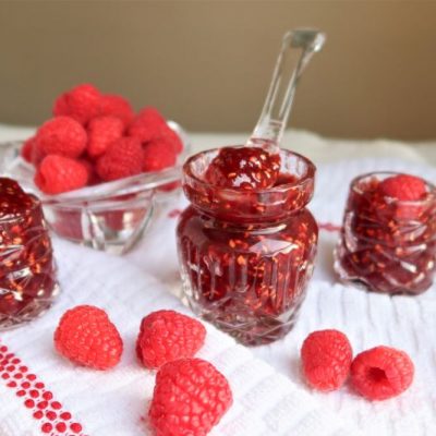Homemade Raspberry Jam in Glass Jar on Textural White Tea Towel