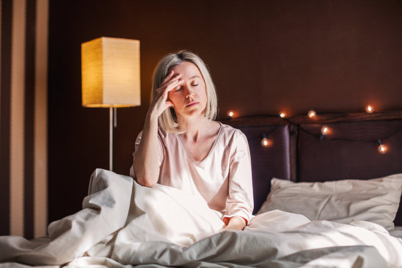 Tired Woman in Bed After Not Getting Enough Sleep and Heart Health Suffering From It