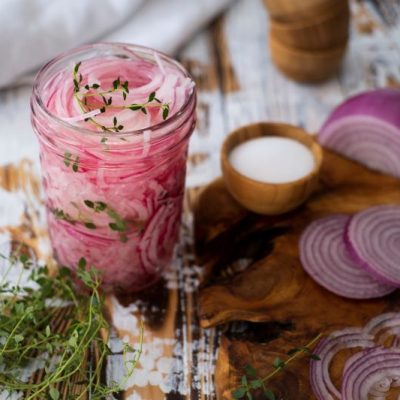 Pickled Red Onion with Thyme in Mason Jar on Wooden Table