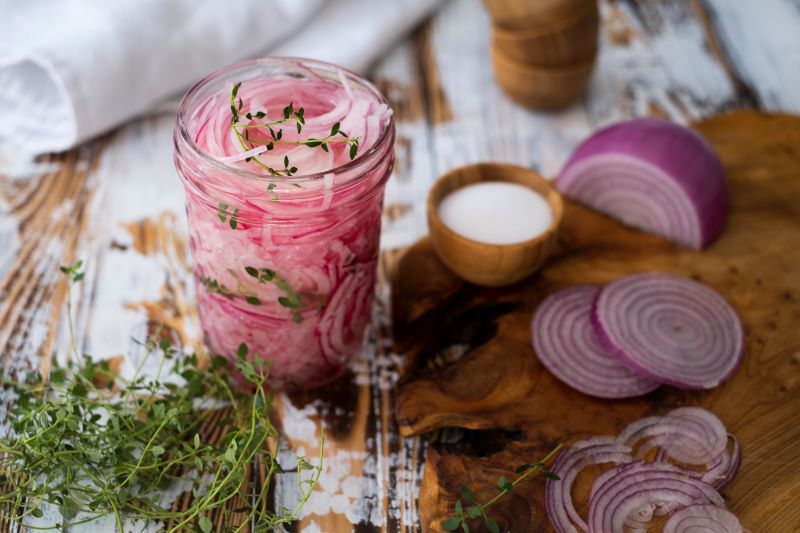 Pickled Red Onion with Thyme in Mason Jar on Wooden Table
