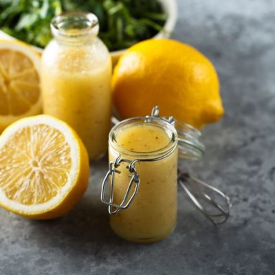 Simple Lemon Dressing in Jars on Counter Surrounded by Lemons