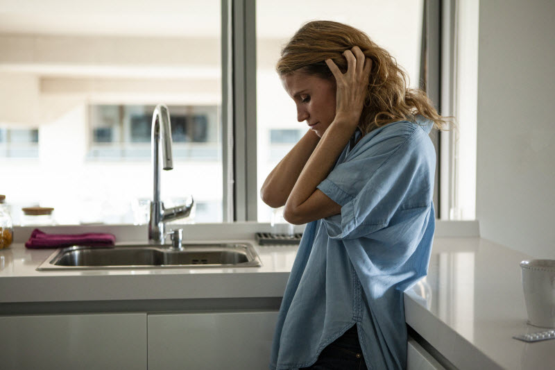 Woman Struggling With How to Deal With Misophonia Covering Ears While Standing in Kitchen