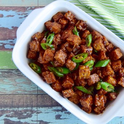 A Serving Dish is Filled With Tempeh Stir Fry, Scallions and Leeks.