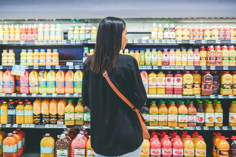 Woman Browsing Juice in Grocery Aisle Wondering About Toxic Metals in Her Favorite Beverages