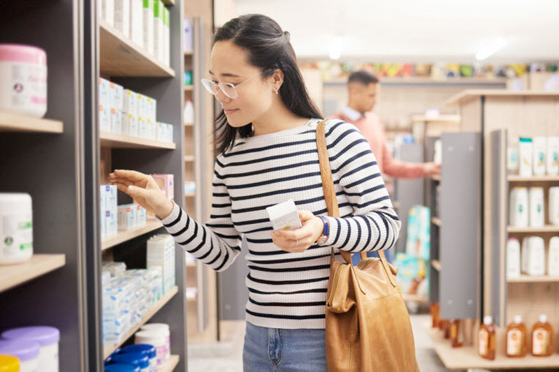 Contemplative Woman Shopping for Supplements Considering Shelf Stable vs Refrigerated Probiotics for Her Digestive Health