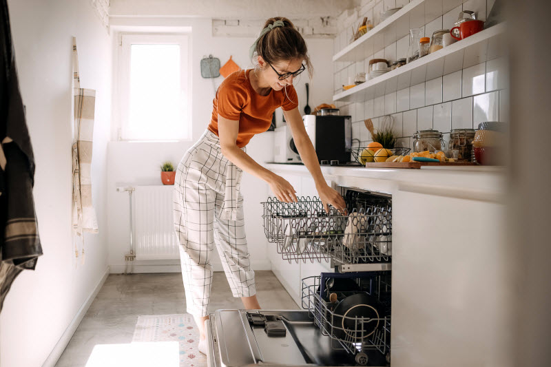 Woman Loading Dishwasher as Part of Holiday Cleaning Strategy