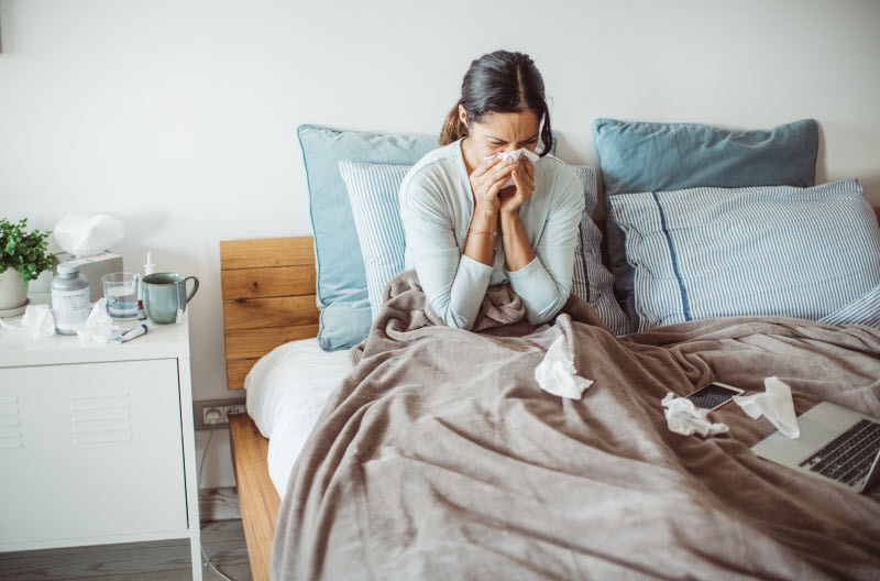 Concept of Stress and Illness Represented by Woman Blowing Nose in Bed