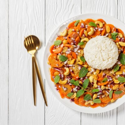 Vegan Curry on a Round Plate with Carrots, Cashews, Herbs and a Bed of Basmati Rice