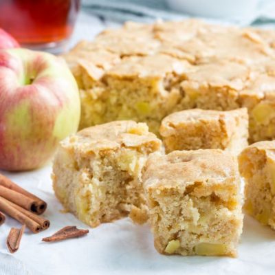 Gluten-Free Caramel Apple Blondies on Counter Next to Apples and Cinnamon Sticks