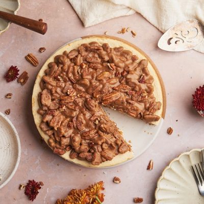 An Overhead View of a Table With a Keto Pecan Pie Cheesecake With One Slice Plated.