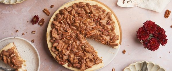 An Overhead View of a Table With a Keto Pecan Pie Cheesecake With One Slice Plated.