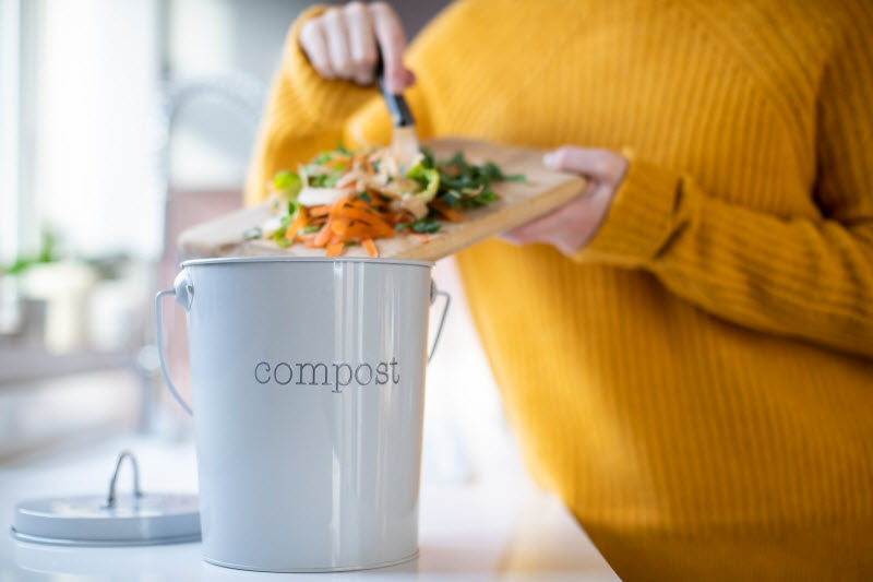 Women Determined to Reduce Food Waste Scraping Vegetable Scraps into Compost Bin