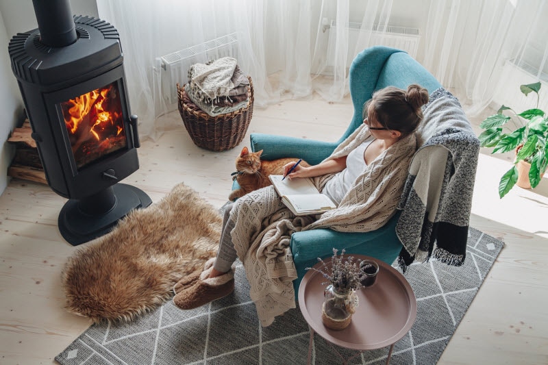 Woman and Cat Sitting Around a Fire as She Enjoys the Health an Wellness Benefits