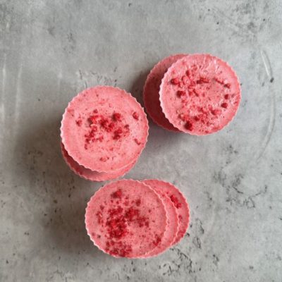 Photo Shot From Above of Dark Pink-Colored Raspberry White Chocolate Candy Cups Against Gray Concrete Surface