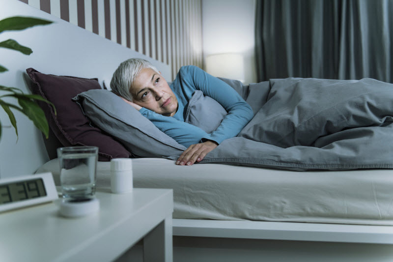 Unsettled-Looking Woman in Bed Struggling with Menopause and Sleep