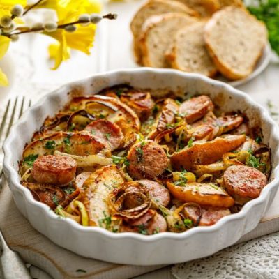 Apple, Leeks & Sausage Casserole in Baking Dish on Table Set With Springtime Daffodils & White Crocheted Doilies