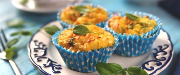 Crustless Mini Quiche Cups in Pretty Blue Paper Liners on Fancy Plate Scattered with Basil Leaves