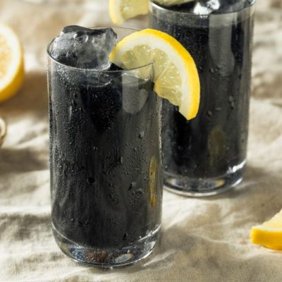 Detoxifying Activated Charcoal Lemonade in Tall Glass with Lemon Wheel Garnish
