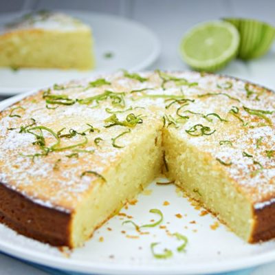Lime Olive Oil Cake Garnished with Lime Zest & Powdered Sugar on White Serving Plate