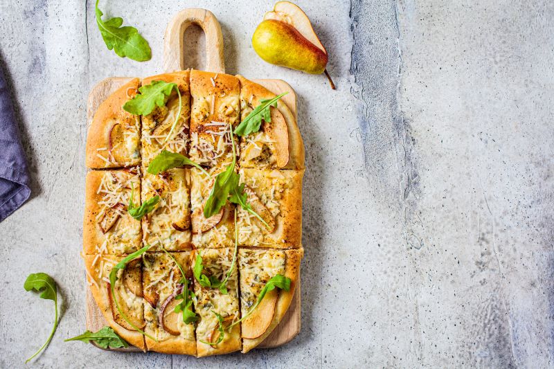 Vegan Pear & Arugula Pizza on Wooden Serving Board Atop Marble Counter
