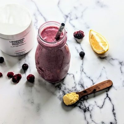 Balancing Berry Smoothie for Women in Glass Jar Next to Product Packaging, Lemon Wedge and a Smattering of Berries on a White Marble Counter