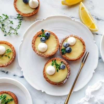 Vegan Mini Lemon Tarts Topped with Blueberries Arranged on a Fancy Plate