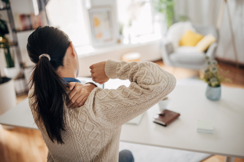 Back View of Woman Holding Shoulder in Pain to Represent Concept of What is a Pinched Nerve