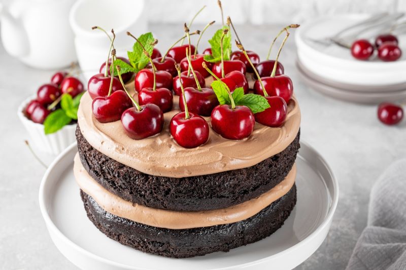 Black Forest Layer Cake Topped With Cherries on Round Serving Platter