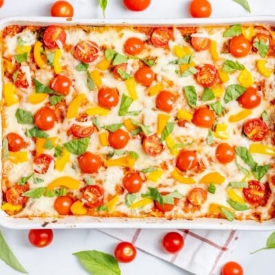Chicken Caprese & Quinoa Casserole in Ceramic Casserole Dish Surrounded by Cherry Tomatoes on the Vine