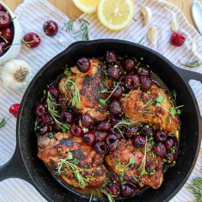 Cherry Chicken in a Cast Iron Skillet Surrounded by Fresh Ingredients