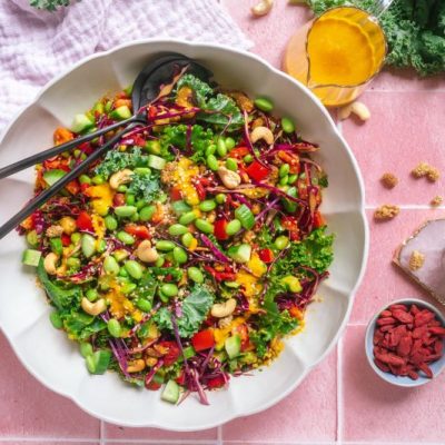 Kale Salad Recipe with Goji Berries, Mulberries, Edamame & Hemp Seeds Drizzled with a Carrot-Ginger Turmeric-Infused Dressing in a Big Serving Bowl on Tiled Tabletop