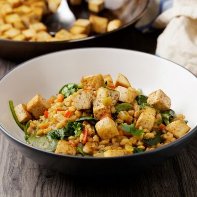 Tofu Curry With Spinach Over Brown Rice in Simple Bowl