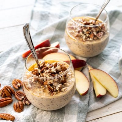 Two Short Glasses Are Filled With Apple Pie Overnight Oats and a Topping of Pecans.