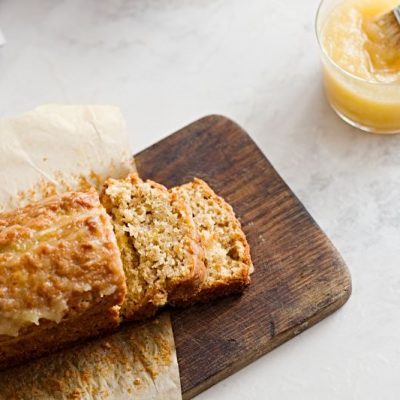 Applesauce Oatmeal Bread with Three Slices Cut and Lying on Wooden Cutting Board Next to Glass Jar of Applesauce