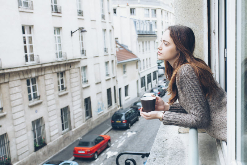 Woman on Balcony of Building on City Street Pondering if the Effects of Noise Pollution are Hurting her Health