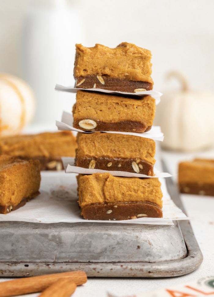 Stacked Pumpkin Pie Squares on Metal Baking Sheet With White Pumpkins in Background