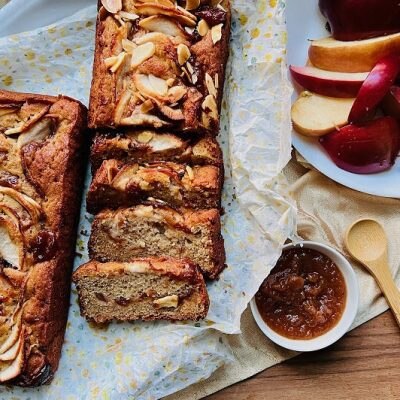 Two Apple Butter Cake Loaves Have Thinly Sliced Apples and Sit Beside Fresh Apple Slices.