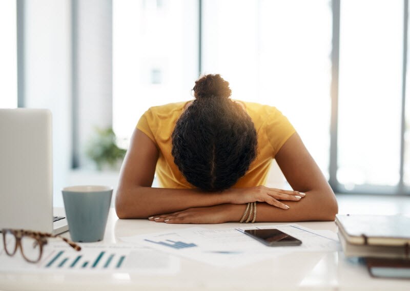 Woman With Head Down on Desk Trying to Cope With Election Stress and Political Anxiety