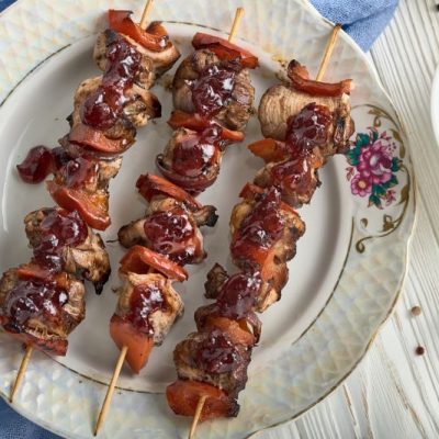 Grilled chicken skewers on fancy plate with cranberry syrup drizzled across them
