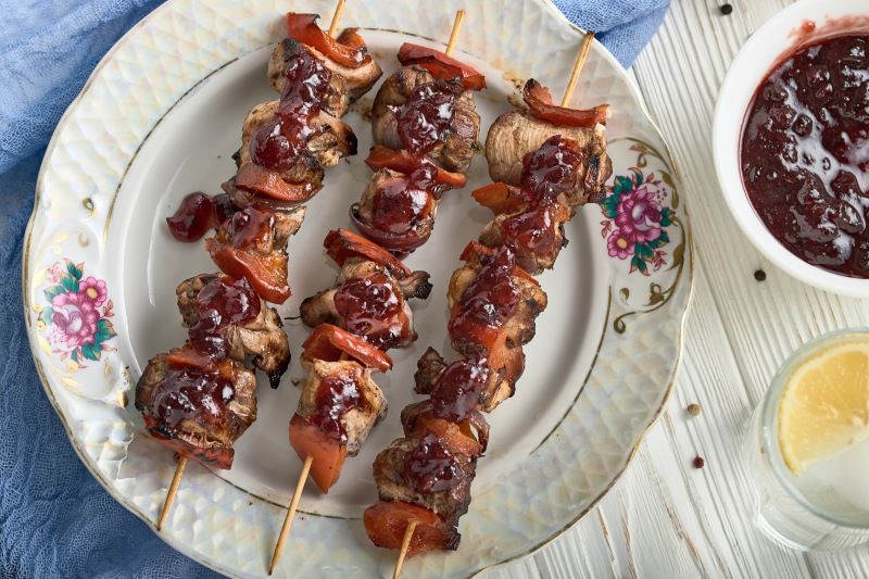 Grilled chicken skewers on fancy plate with cranberry syrup drizzled across them