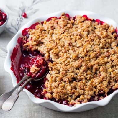 Cranberry crumble dessert on a round pie pan on a holiday table cloth