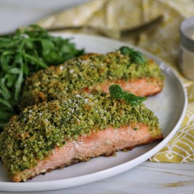Two Panko Crusted Salmon Filets are on a White Dinner Plate With a Side of Arugula Salad.