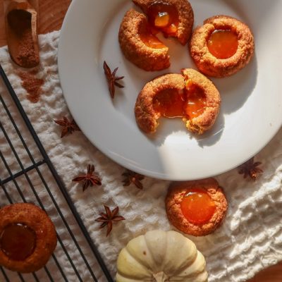 Pumpkin Thumbprint Cookies Sit on a White Plate With Pumpkin Butter in the Center.
